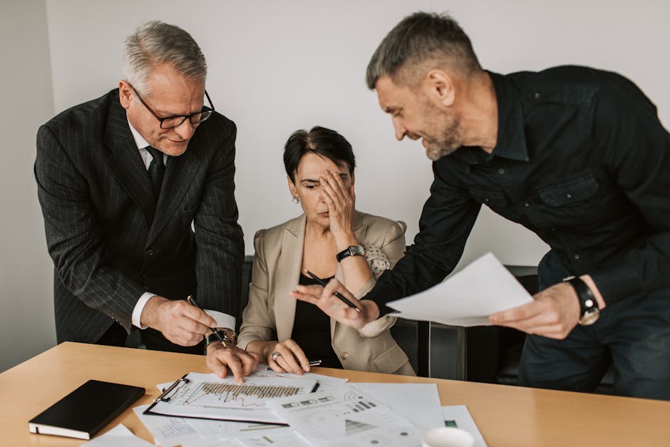 Business team in a tense meeting analyzing charts and reports at an office desk.